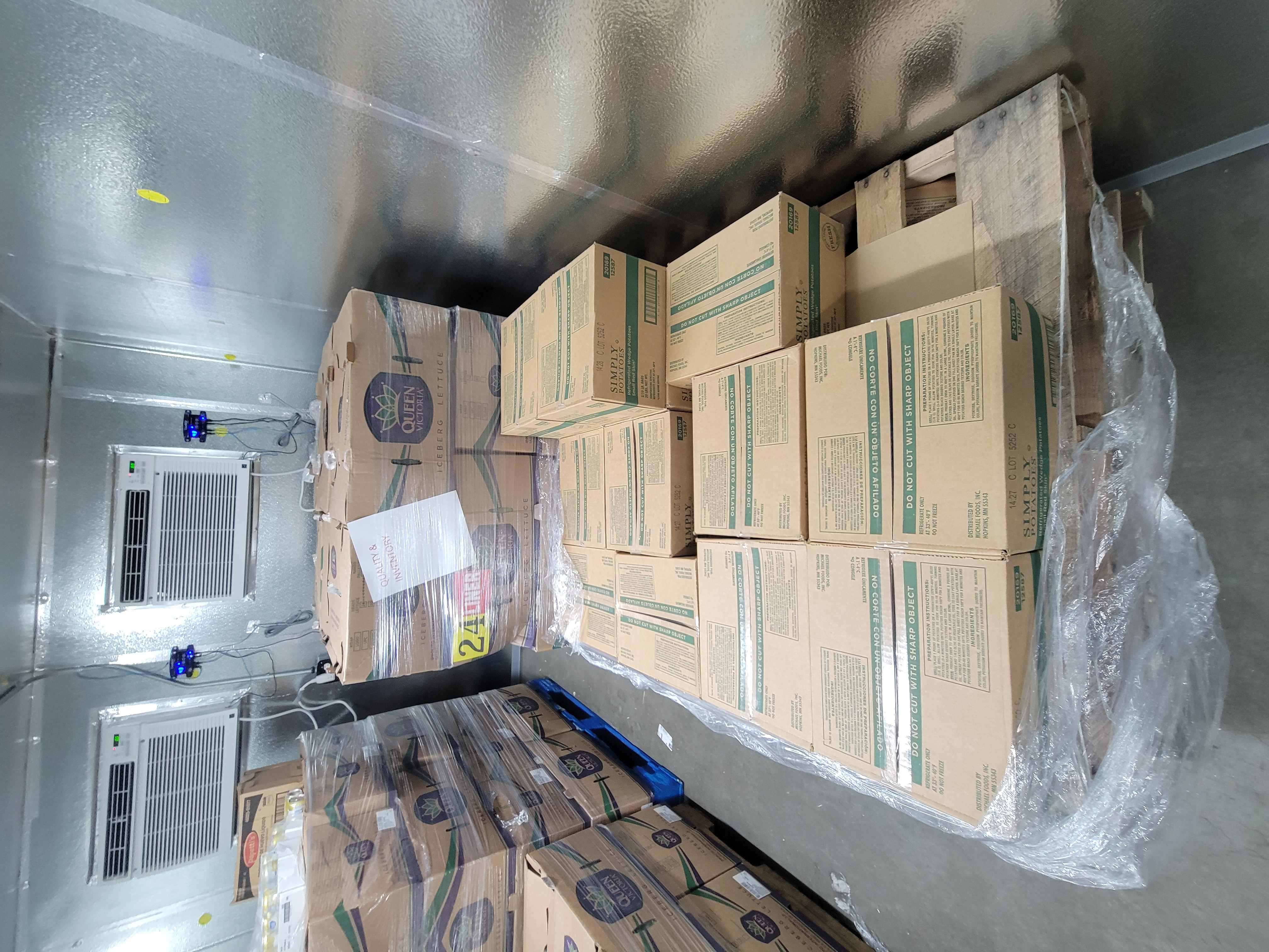 Pallet of wedge potatoes surrounded by pallets of boxes of iceburg lettuce.